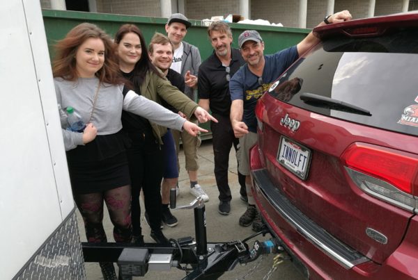 Six people smiling and pointing at a car register plate with the word Innolift.