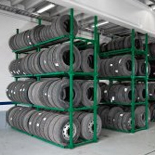 Tires stored vertically in two tire racks.