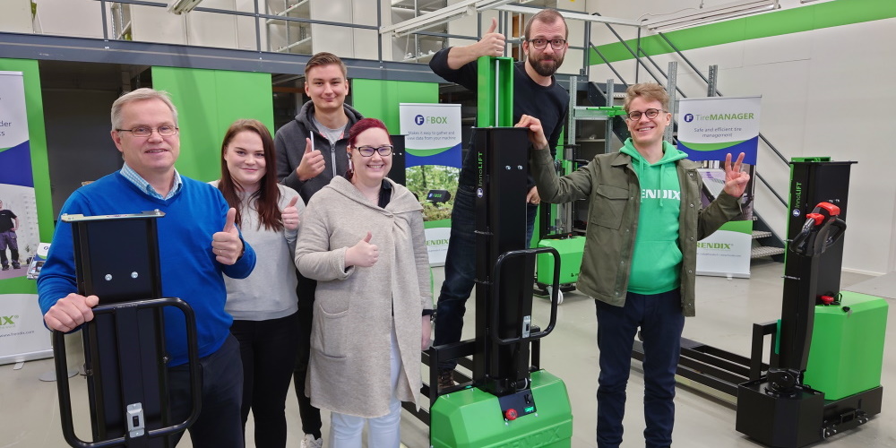 A group of people smiling and giving the thumbs up between InnoLIFT machines.