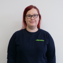 A red haired woman with glasses in a dark blue shirt from the chest up.